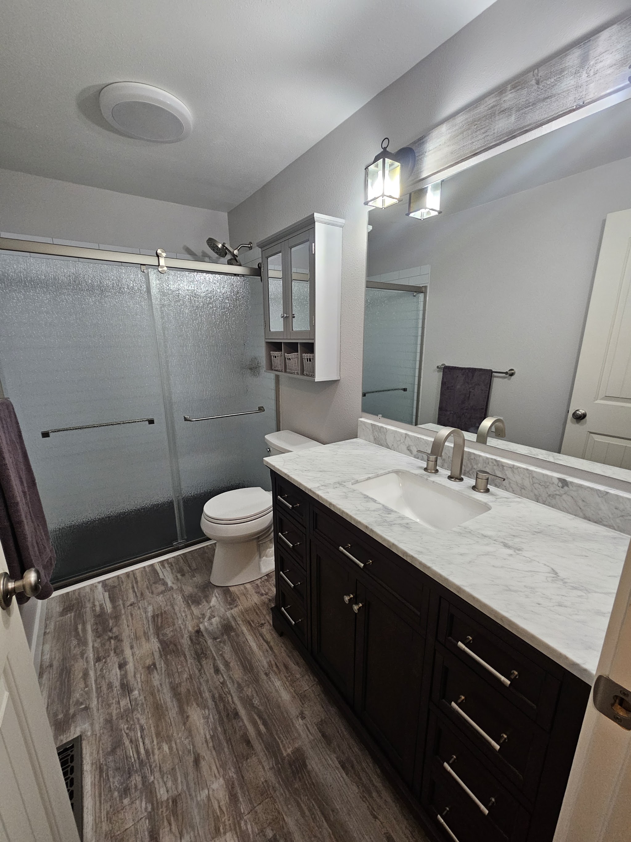 Modern gray-tiled shower and dark vanity after the remodel